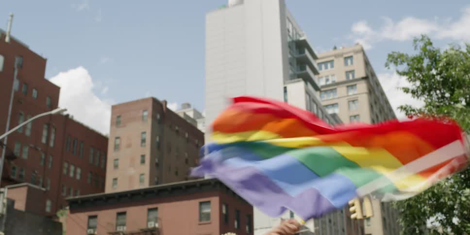 A person waves a gay pride flag in a city