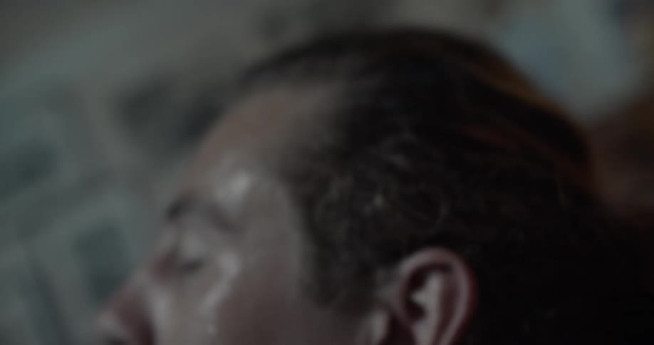 A man wipes his sweaty forehead with his arm