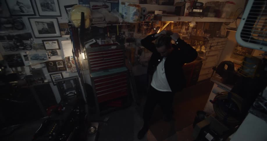 A man walks up to a motorcycle in a workshop