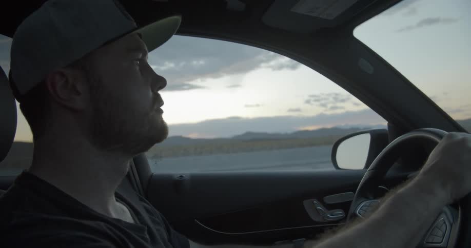 A man talks and points while driving