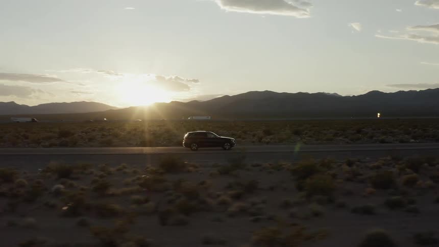 A car drives on a rural street at sunset