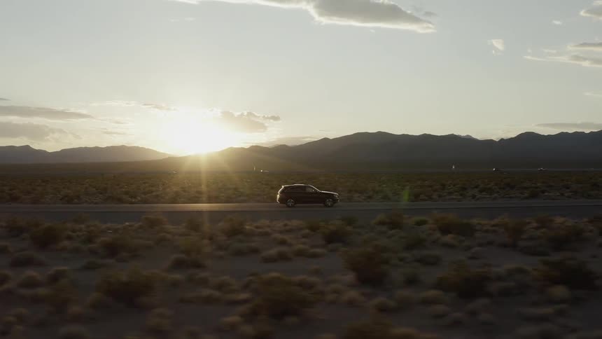Car traveling on desolate mountain highway at sunset