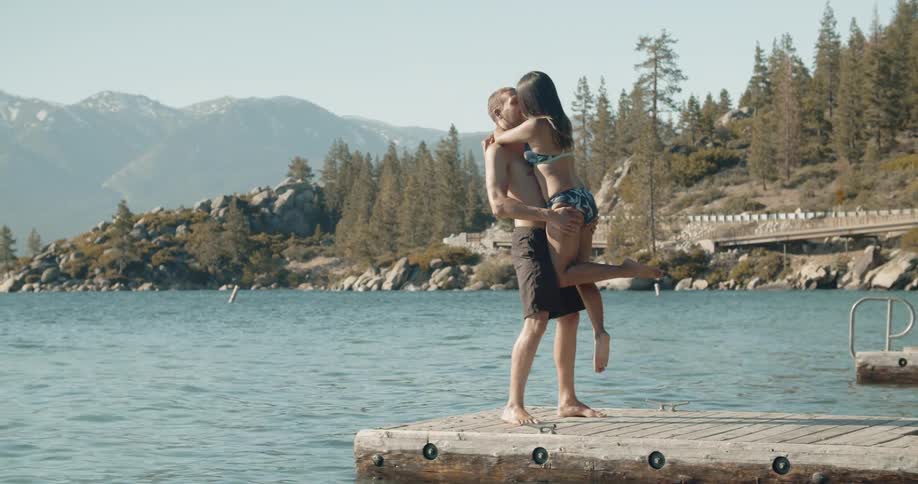A woman is hugging and kissing a man on the pier