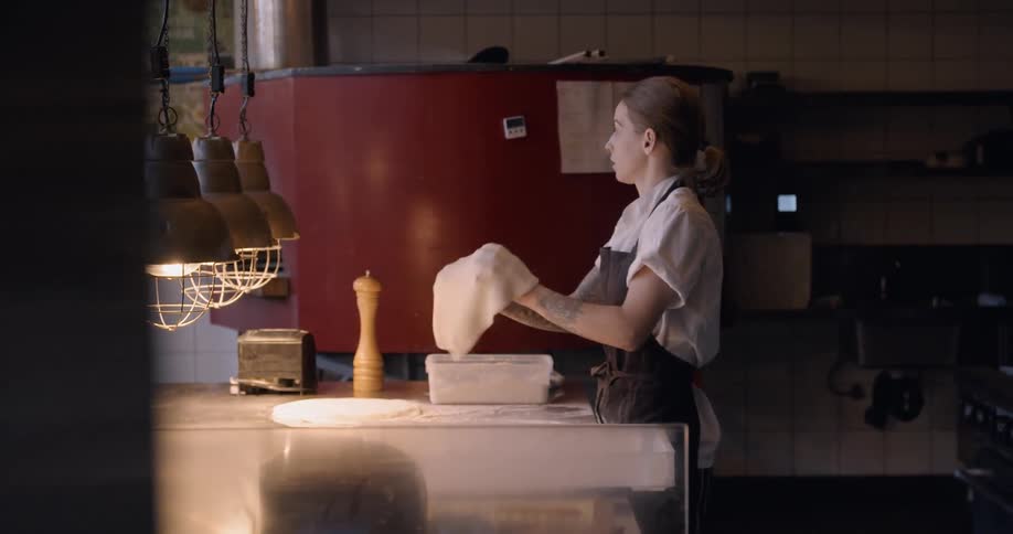 Two chefs make pizza in a restaurant kitchen