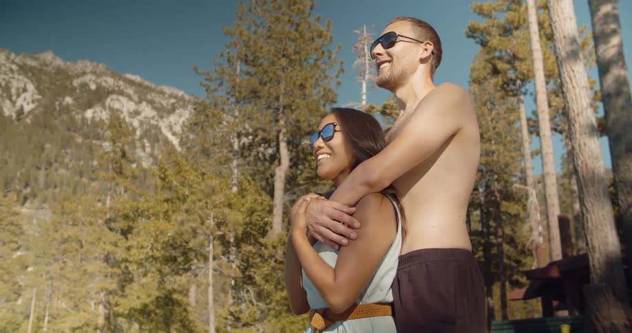 A man has his arms around a woman as they are standing in a natural setting in daylight