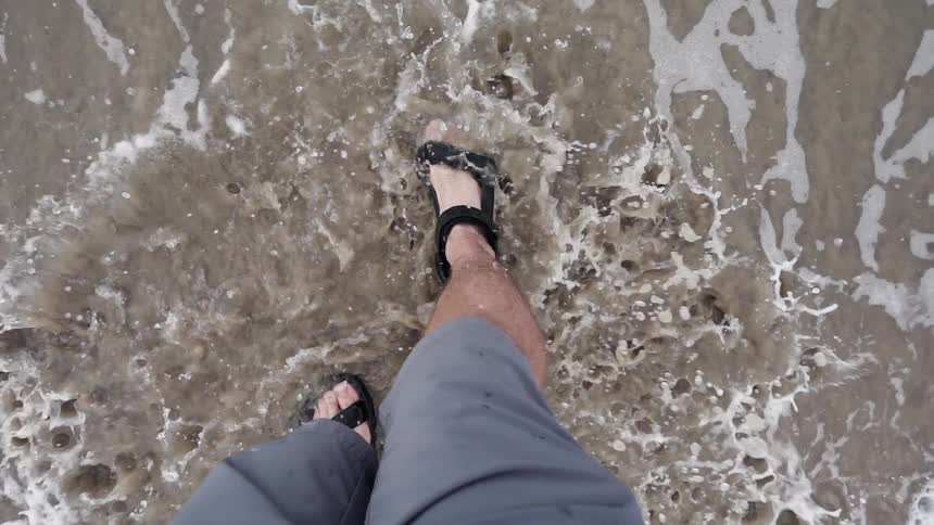 Water splashes around a man wading in ocean waves