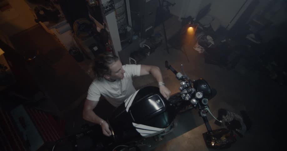 The man is working on his motorcycle in the garage