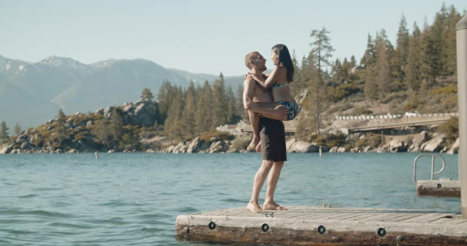 A couple flirts on a lake dock