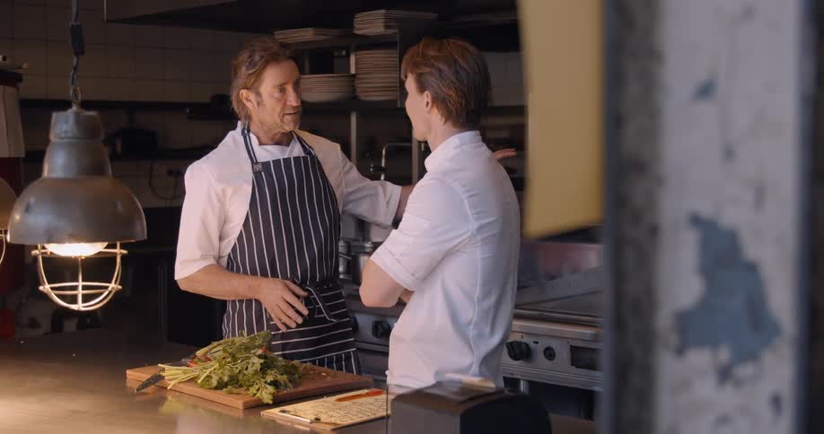 Two chefs talk in the kitchen