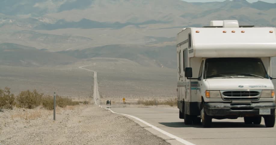 A camper travels on a desert road on a sunny day