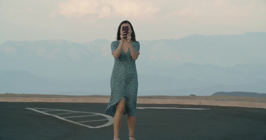 A woman smiles and takes a photograph on a windy day