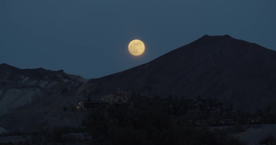 The moon glows above a mountain