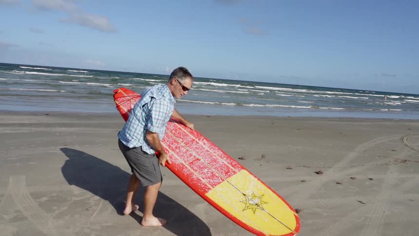 A man carries a surfboard on a beach