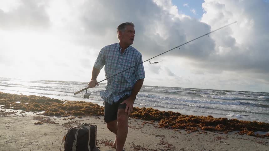 Man holding a fishing pole on the beach