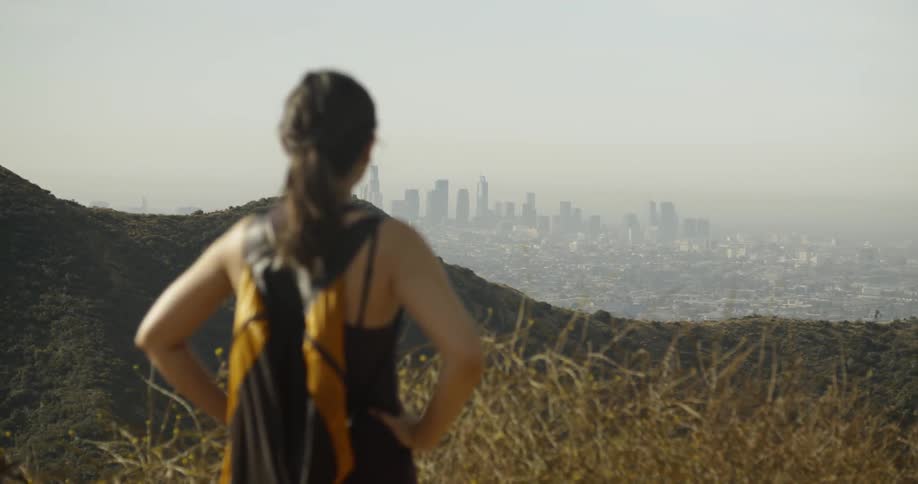 A woman looks at the city from top of a hill