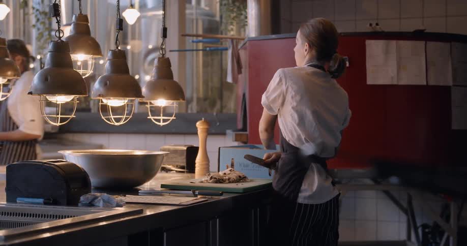 Woman chops food on a cutting board in a restaurant
