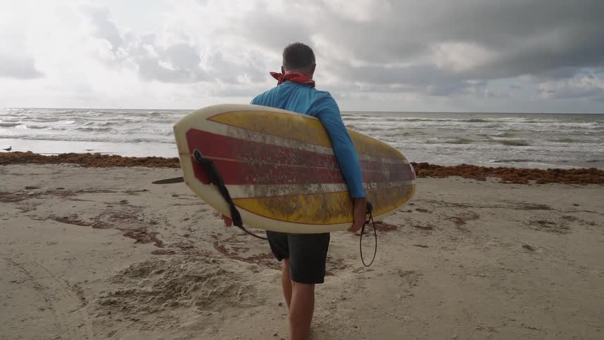 A man travels to the water with a surfboard