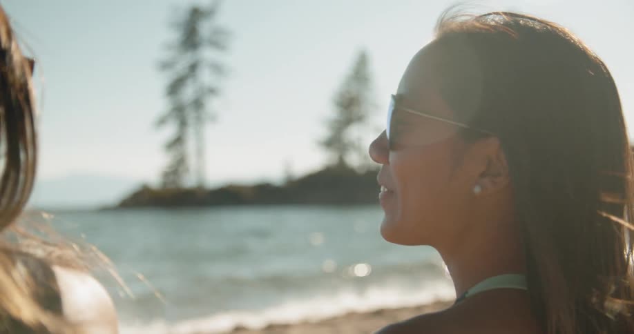 Two women laugh while talking on a beach