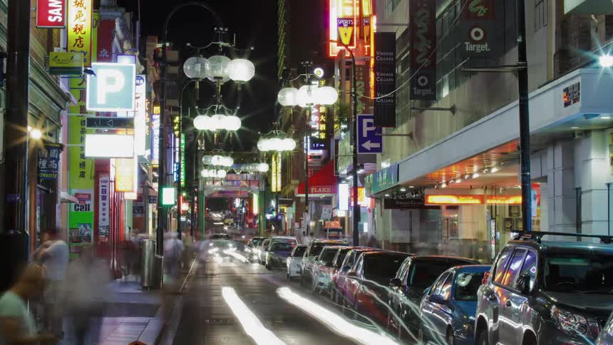 Pedestrians and cars travel in a city at night