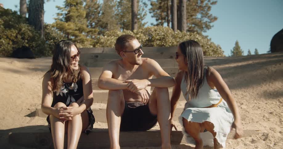 A woman joins a couple sitting on sandy steps