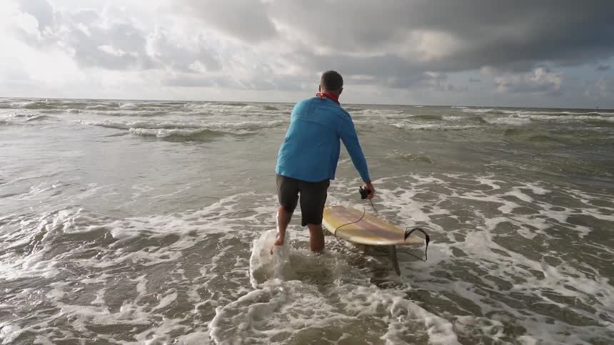The man drops is surfboard in the water