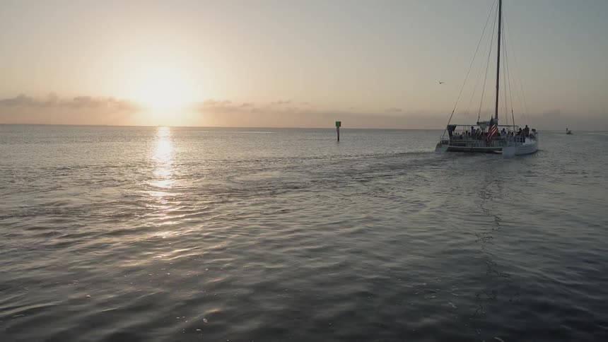 A boat floats on an ocean at sunset