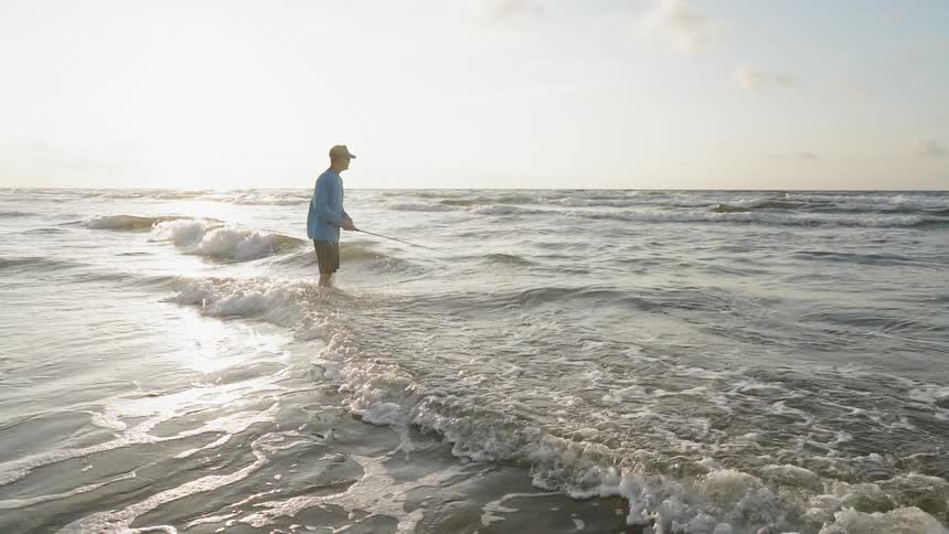 A man stands in the waves fishing
