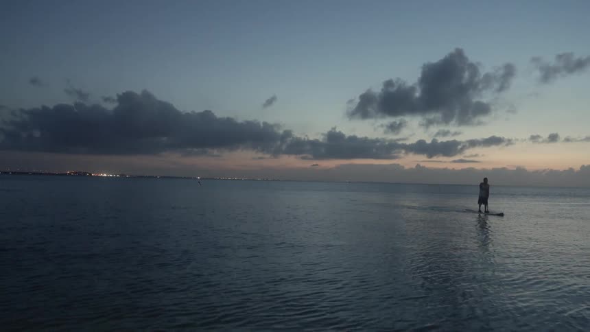 A man is rowing at sunset