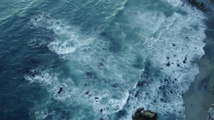 The rough waves crash against the sand