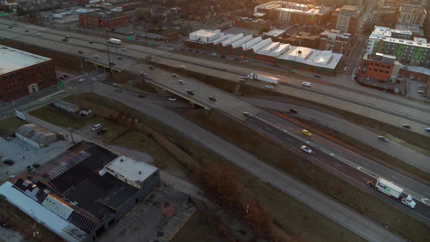 Cars drive on a city highway at sunset