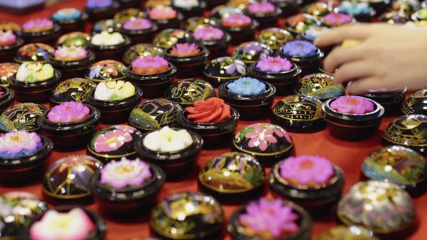 A person is picking through flowered items on a table