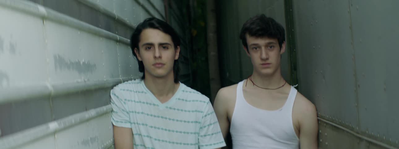 Two men stand between metal walls