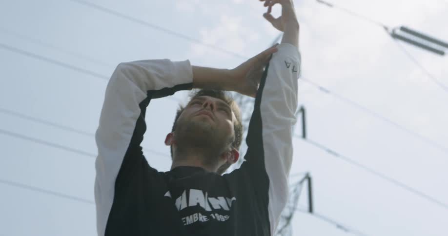 Man moves his arms as he looks up at the sunny sky