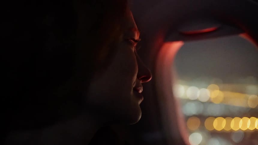 A woman smiles while looking out of a plane window