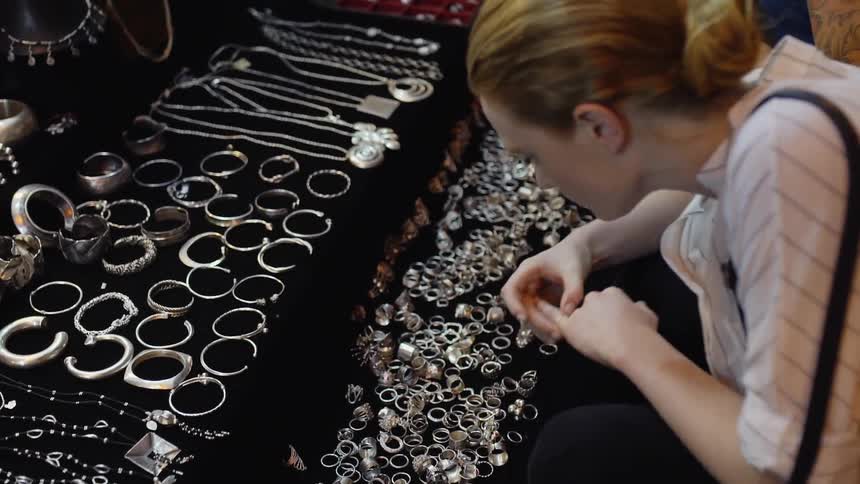 A woman searches through jewelry on a table