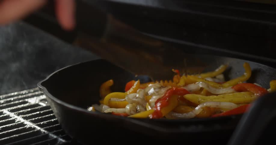 A person is cooking peppers in a pan