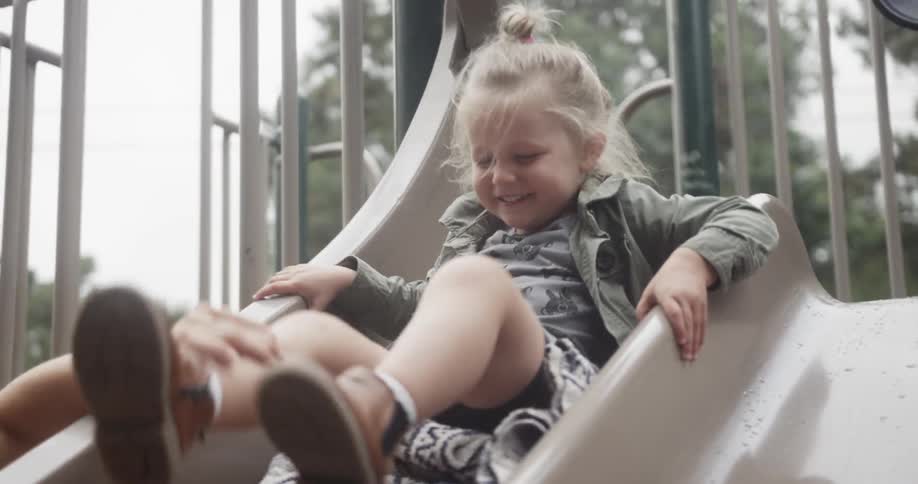 Kid laughing and sliding down slide