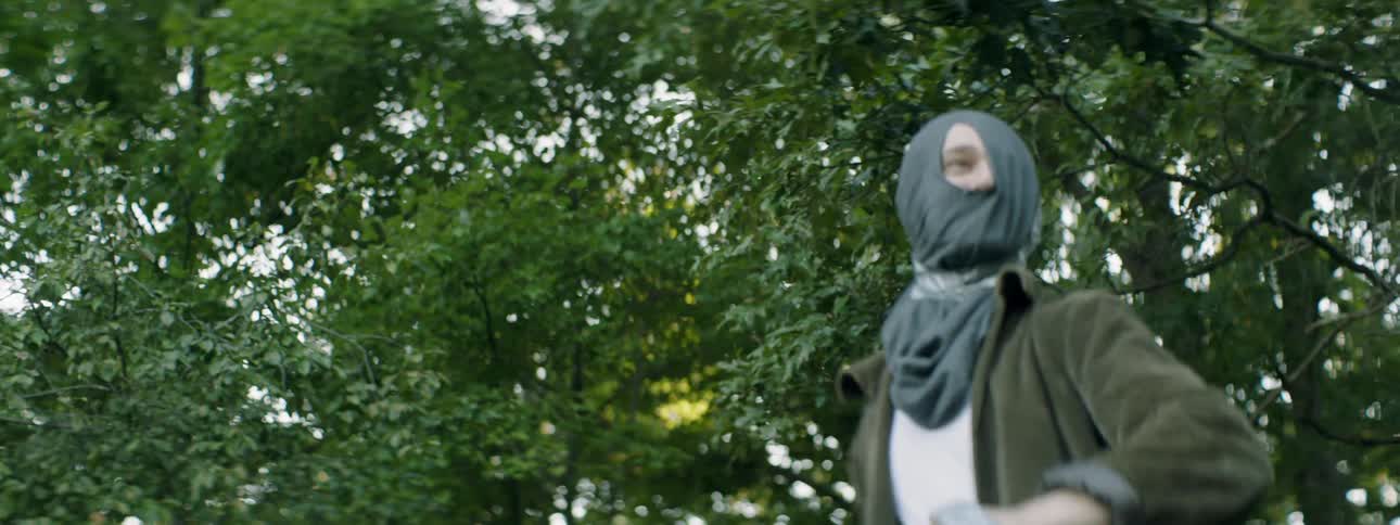 A person spins outside with their face covered
