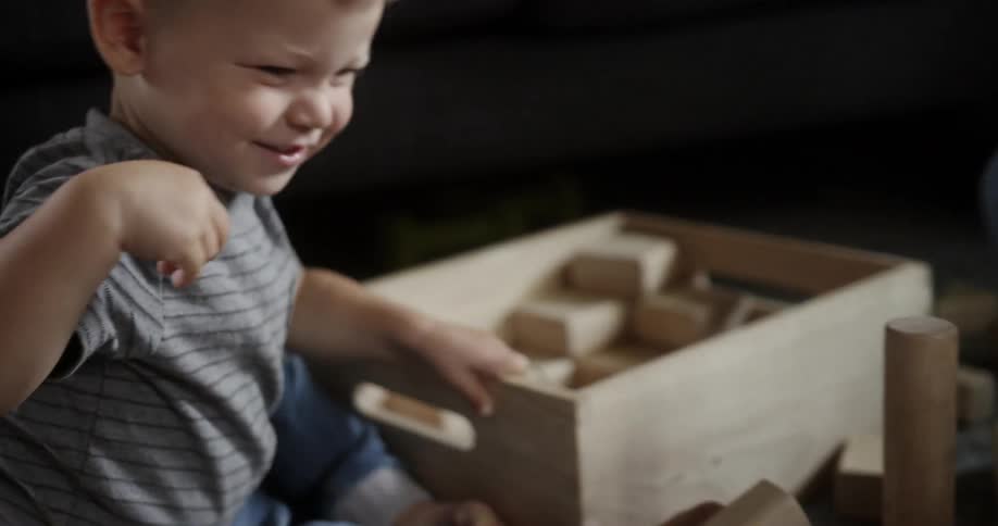 Kid playing with block toys and smiling
