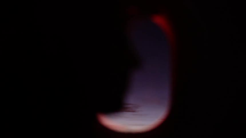 A person sits in the window seat of an airplane