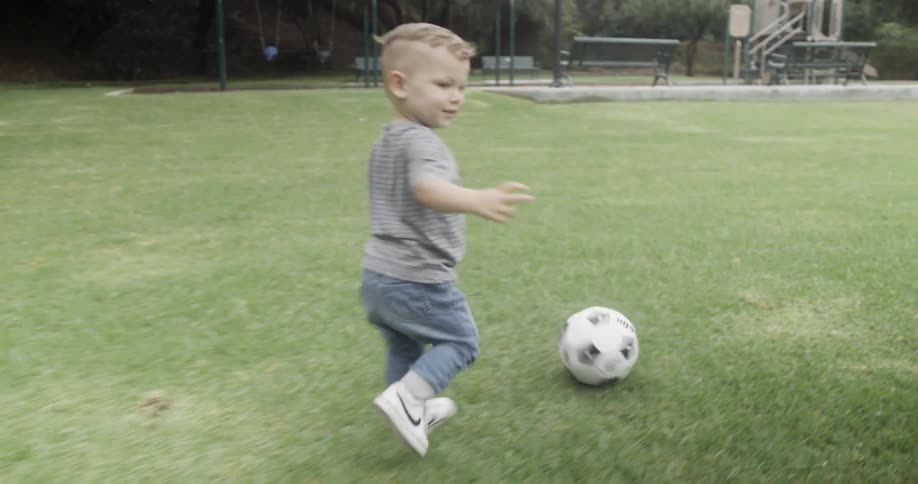 A young boy plays with a soccer ball at a park