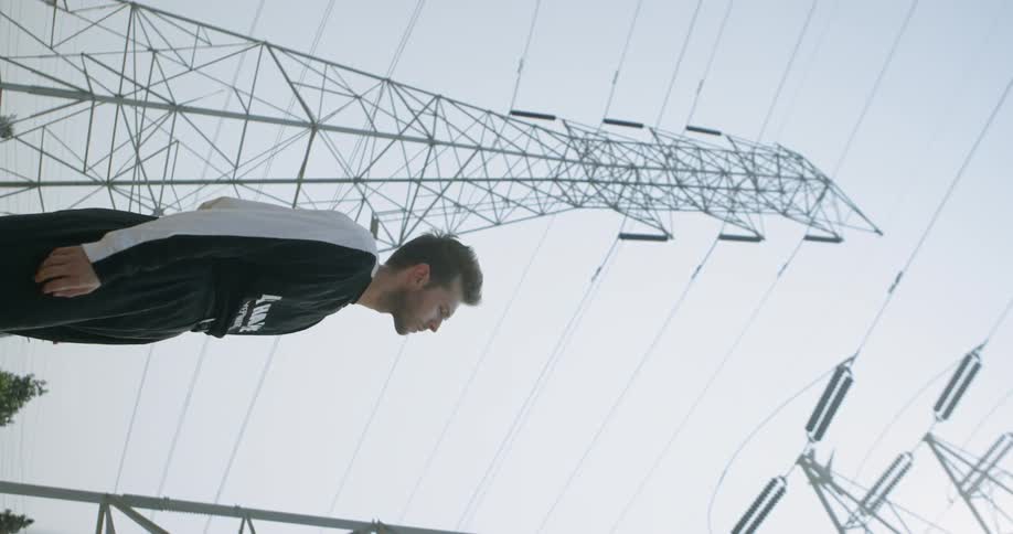 Man stands near a tower and watches a jet fly by