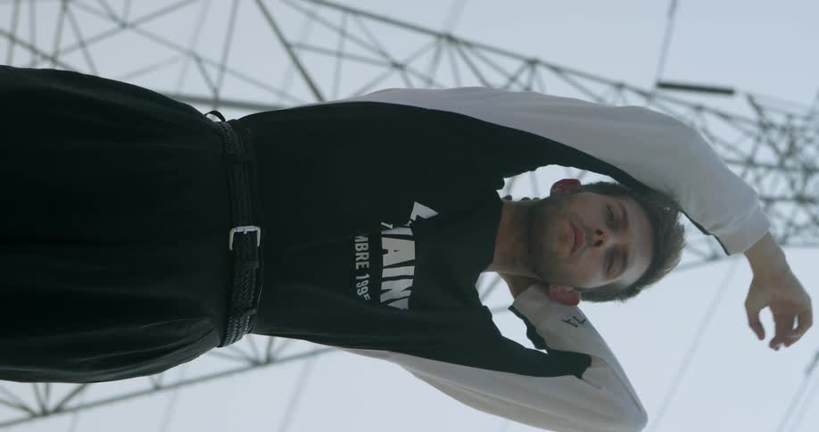 Man stretches his arms as he stands near a tower