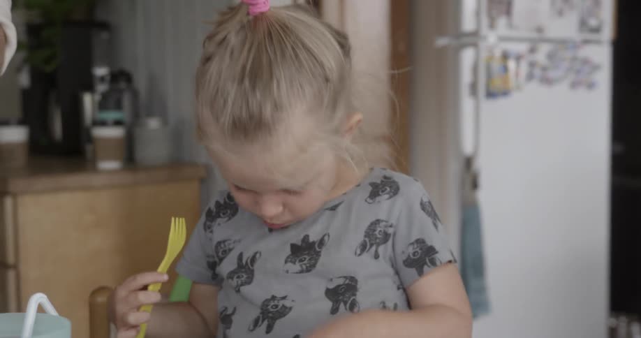 Young child eats pancakes with a plastic fork