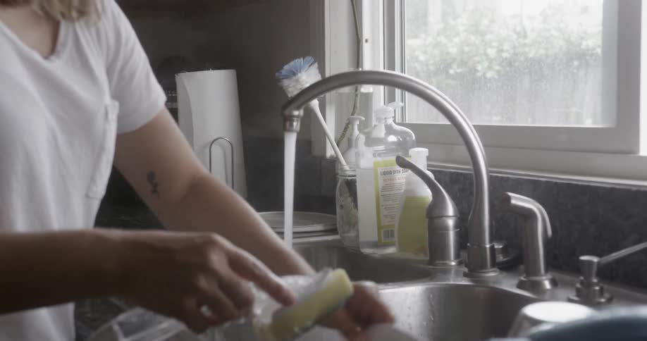 A woman washes dishes at home