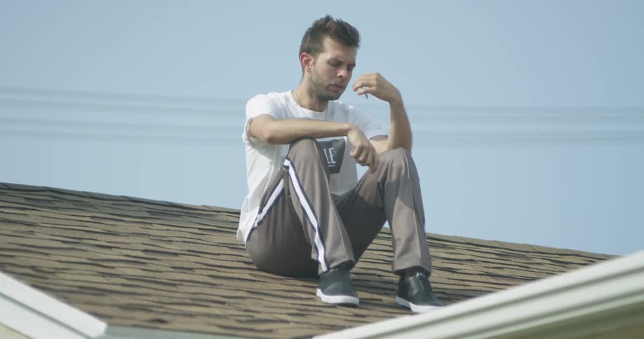 A man smokes on top of a roof