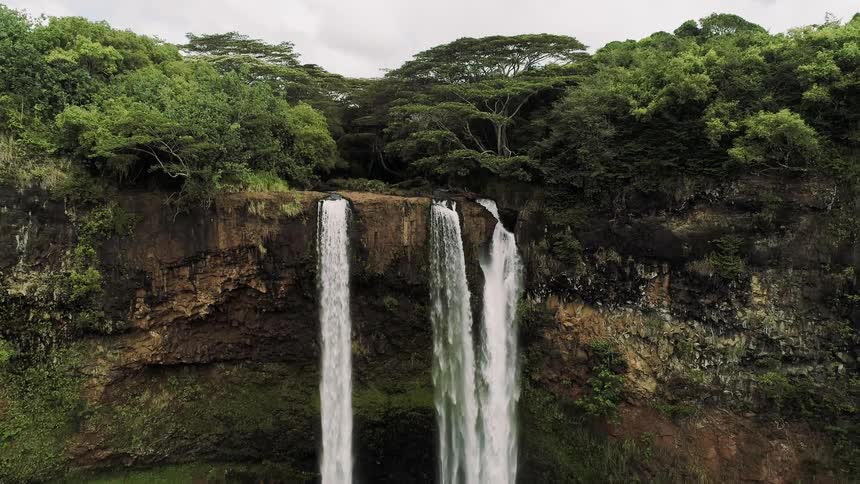 The waterfall pours off the high cliff