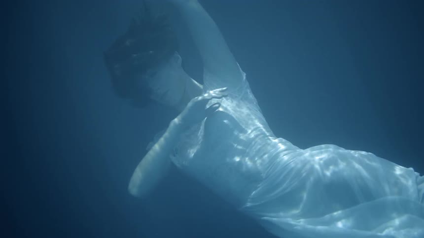 Woman in a white dress floats under the water