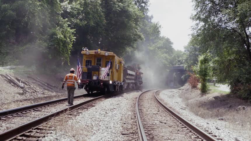 A worker walks behind a stopped train