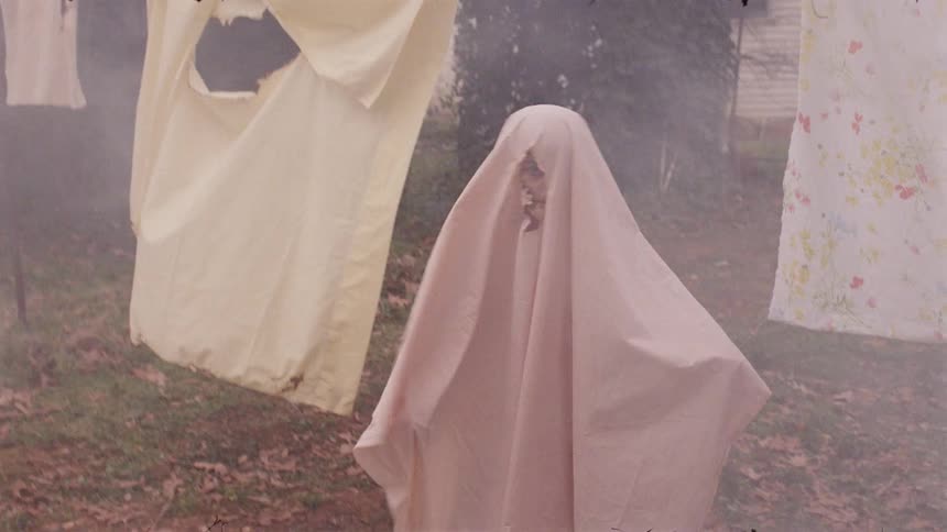 A young boy plays outside with a sheet on